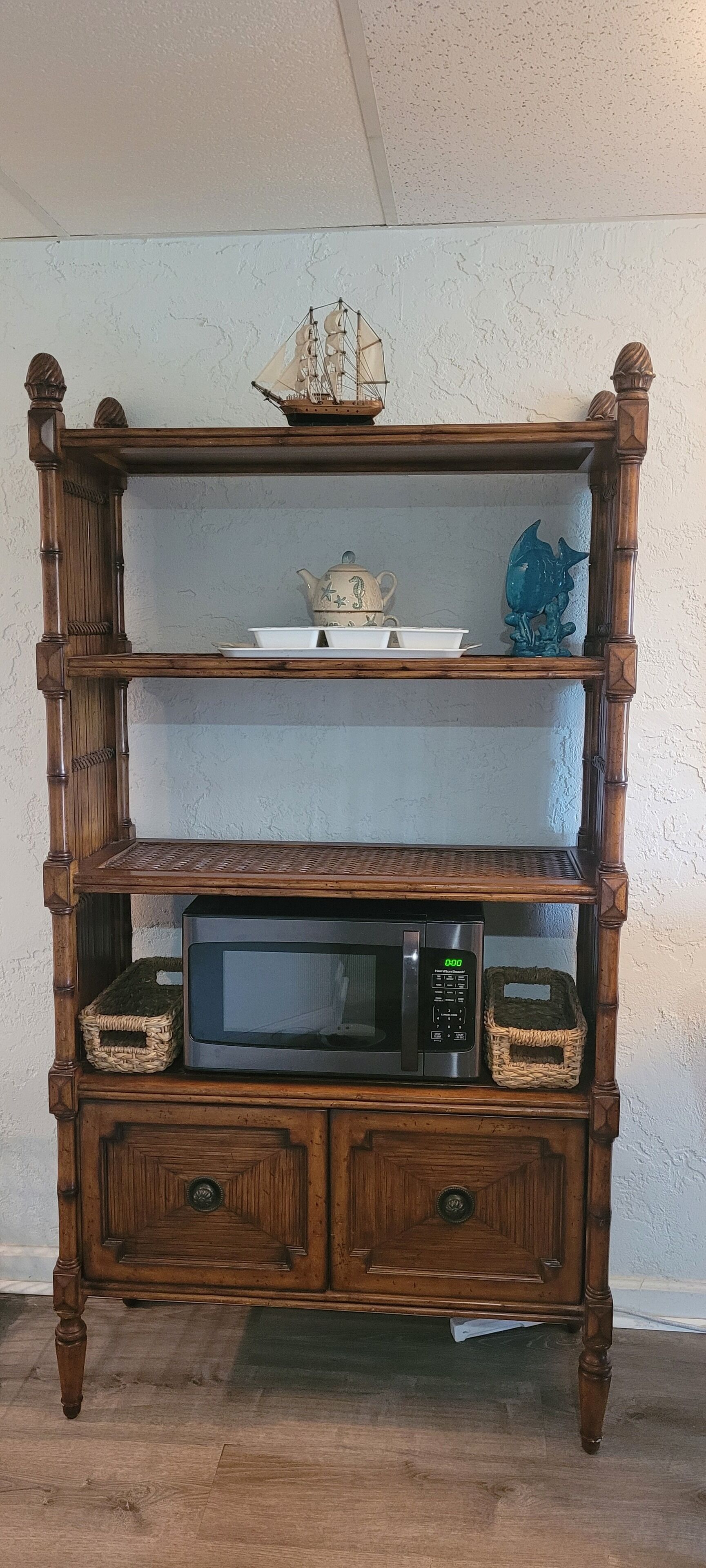 A wooden multi-tiered shelf unit with a ship model, a teapot, and decorative items.