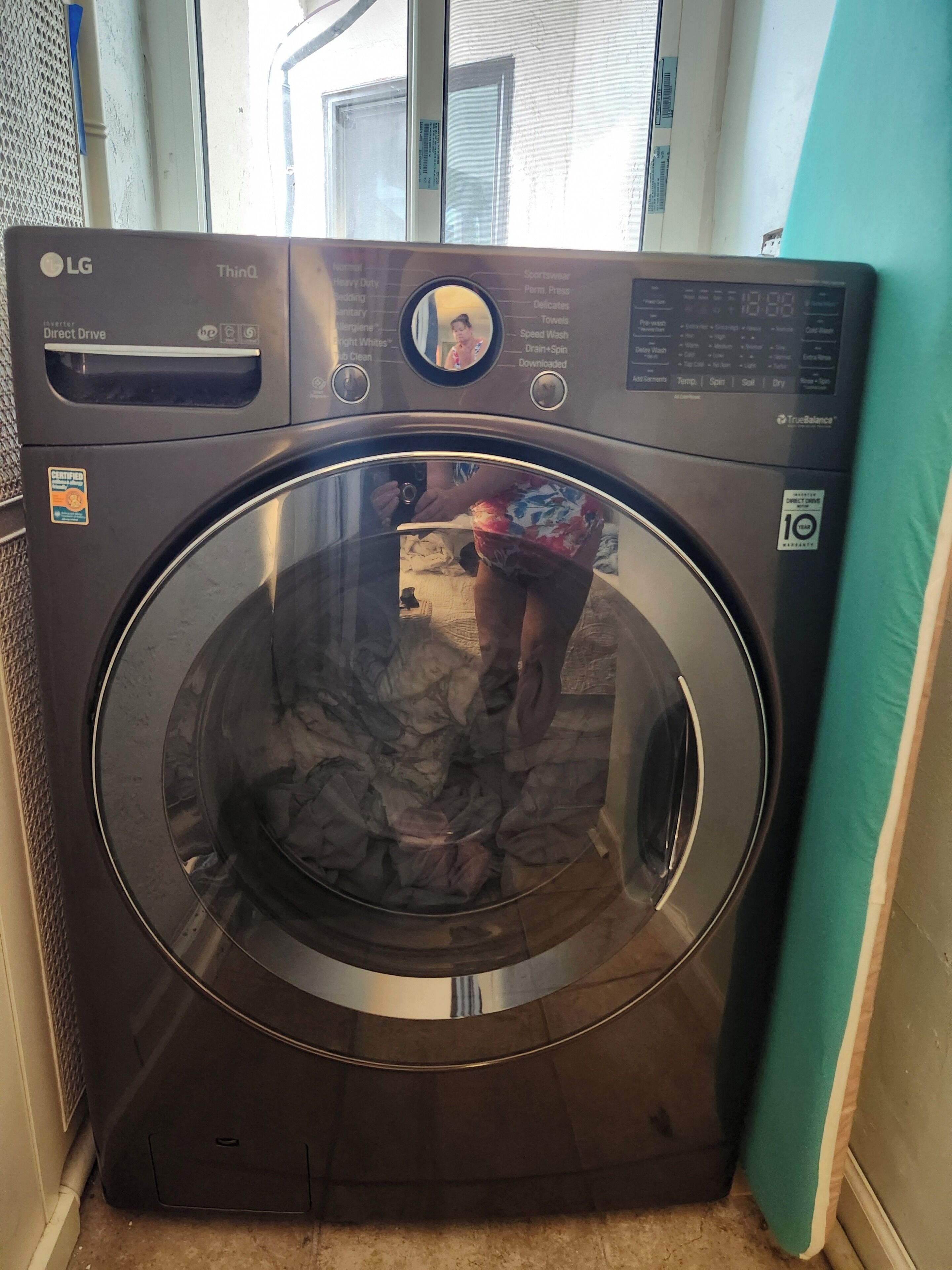 A front-loading LG washing machine with a digital display, a control panel, and a certification sticker.