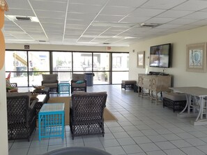 Relax in a spacious area with a high ceiling, featuring a grid pattern and comfortable seating for unwinding or watching TV.