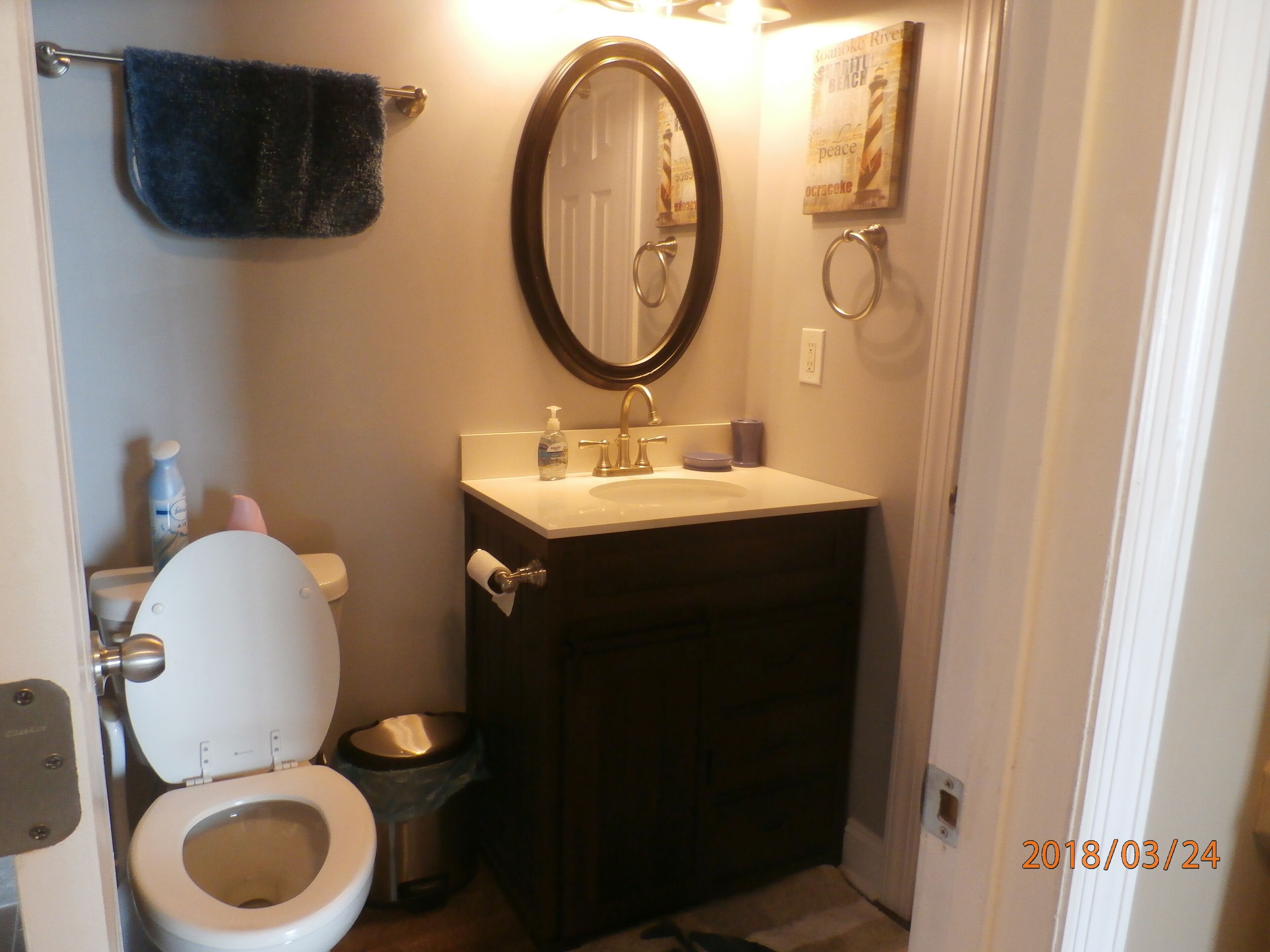A bathroom with a toilet, sink, and mirror.