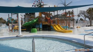 A water park with a pool, slides, and play structures.