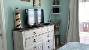 A bedroom with a bed, a dresser, a television, and wall decorations.