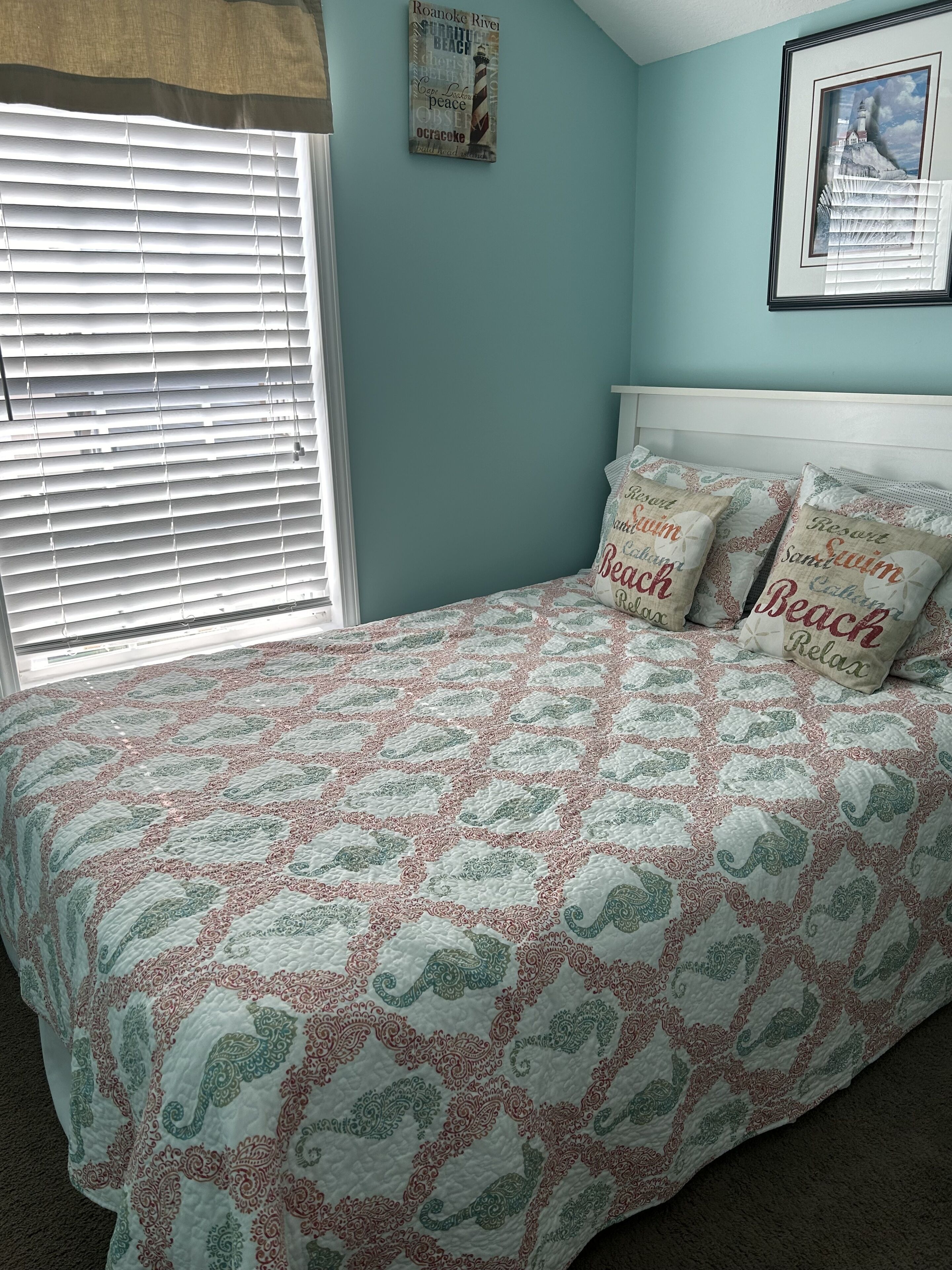 Un dormitorio con cama, ventana con persianas, un cuadro en la pared y cabecera.