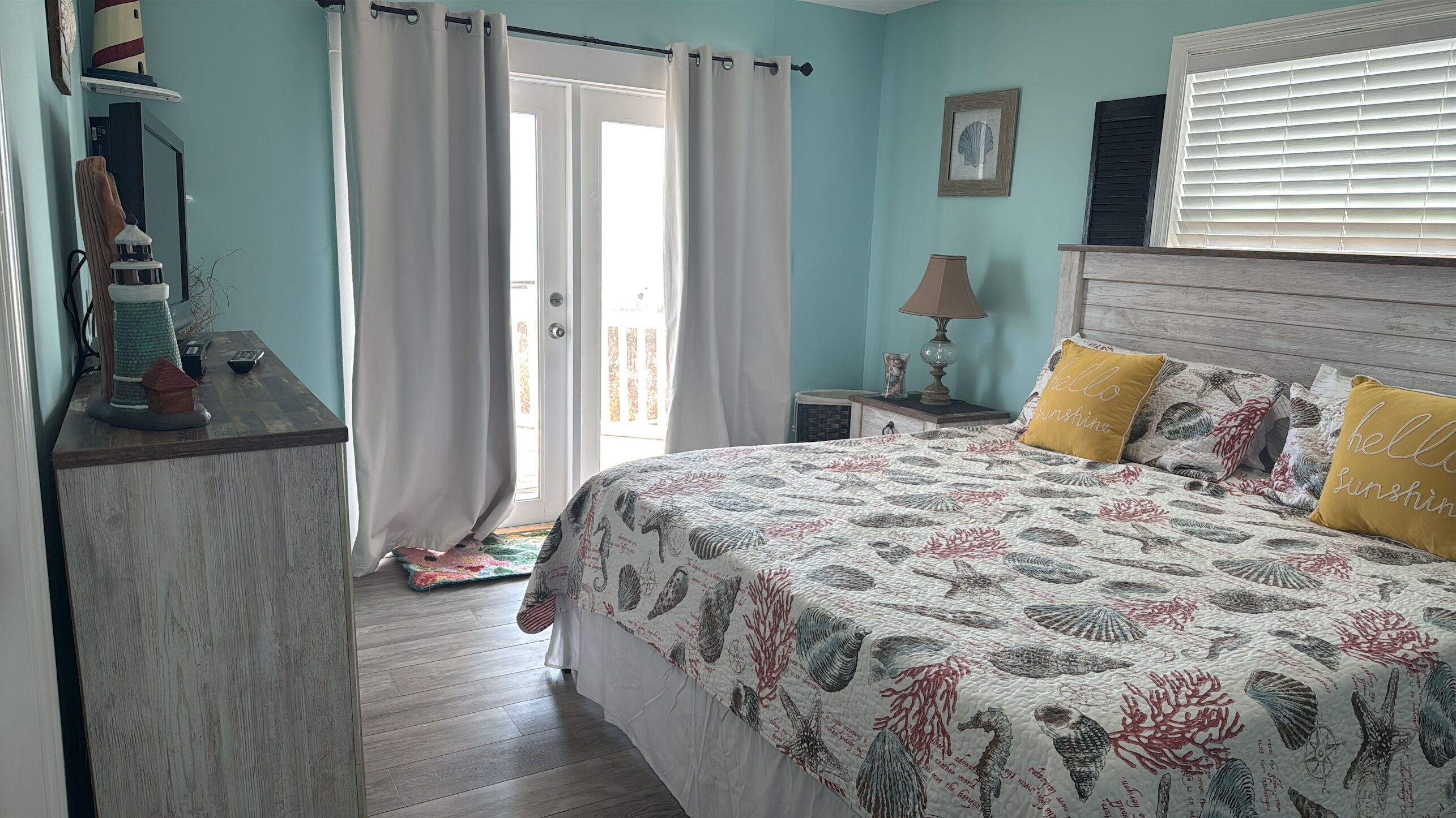 Une chambre à coucher avec un lit, des rideaux, une lampe, une table de chevet et une fenêtre avec des stores.