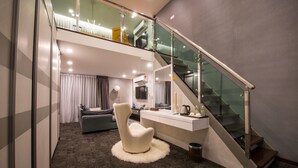 A modern hotel room with a spacious living area, a glass staircase, and a cozy seating area. - Asiatic Hotel (Malacca City)