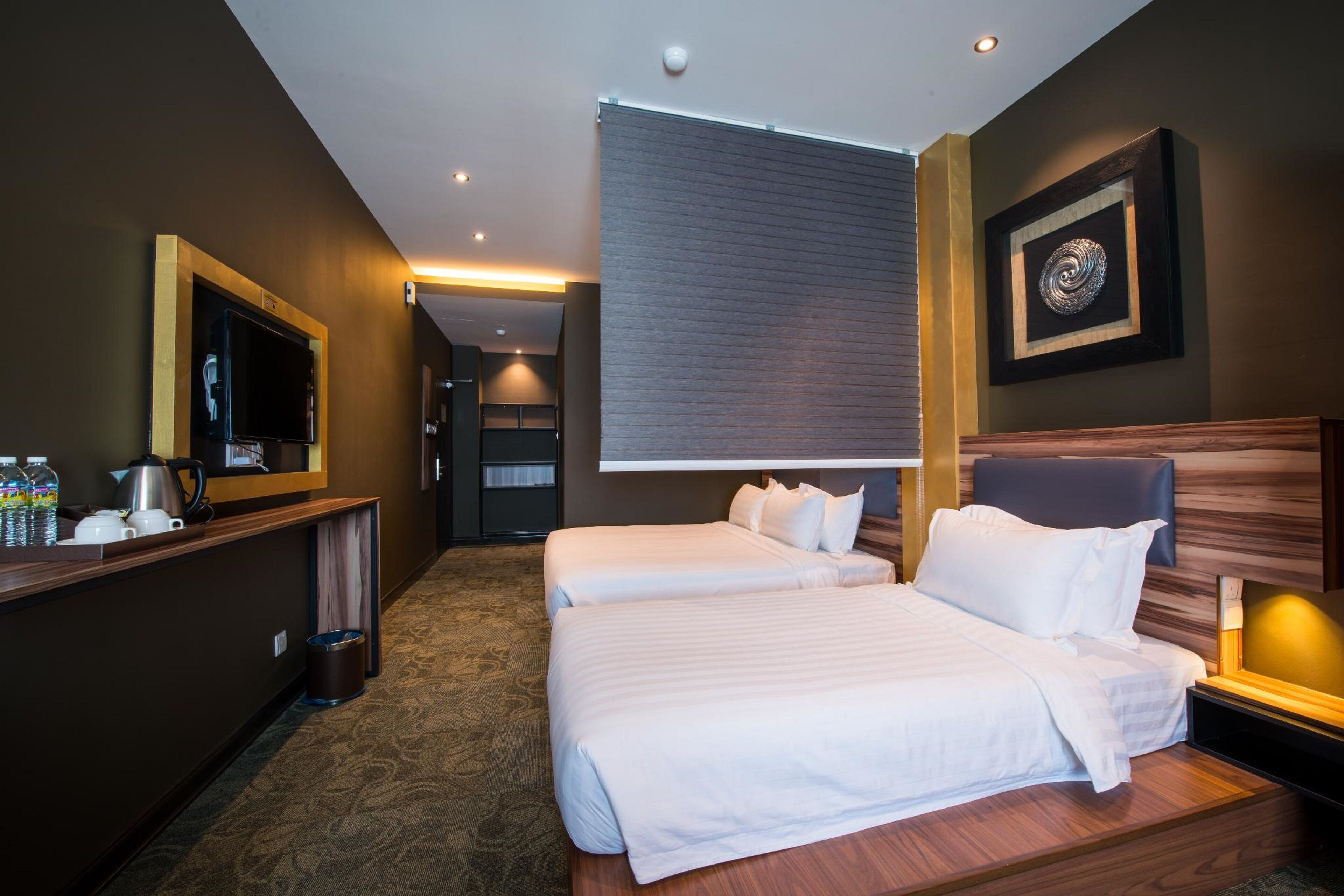 Een hotelkamer met twee bedden, een televisie, een koffiezetapparaat en een ingelijst schilderij aan de muur.
