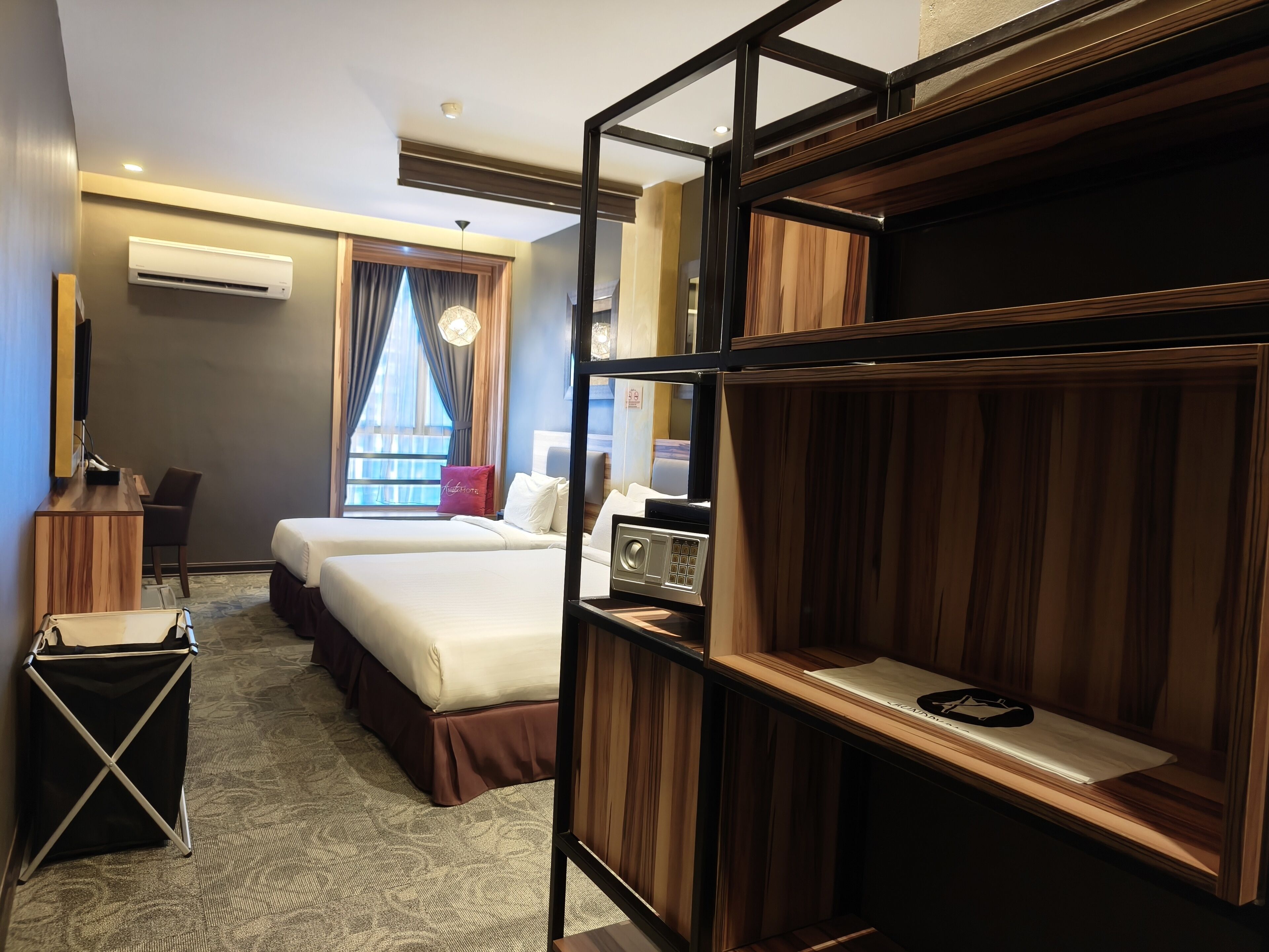A hotel room with two beds, a desk, a chair, a TV, and a wardrobe.