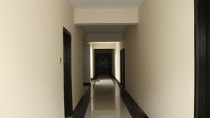 Un long couloir étroit, avec un sol carrelé de noir et de blanc et des murs de couleur beige.
