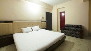 Une chambre d’hôtel avec un grand lit, un canapé, un ventilateur de plafond et une porte.