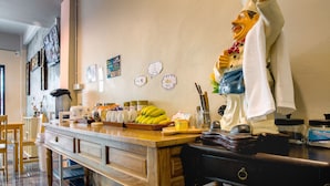 A kitchen counter with a fruit bowl, a coffee machine, and a decorative statue. - The Guest Hotel - Hostel (Krabi)