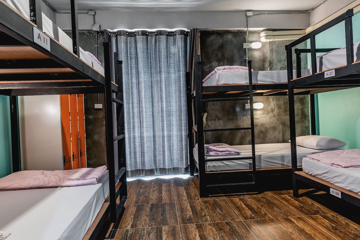 Un dormitorio con literas, suelo de madera, una cortina y una puerta.