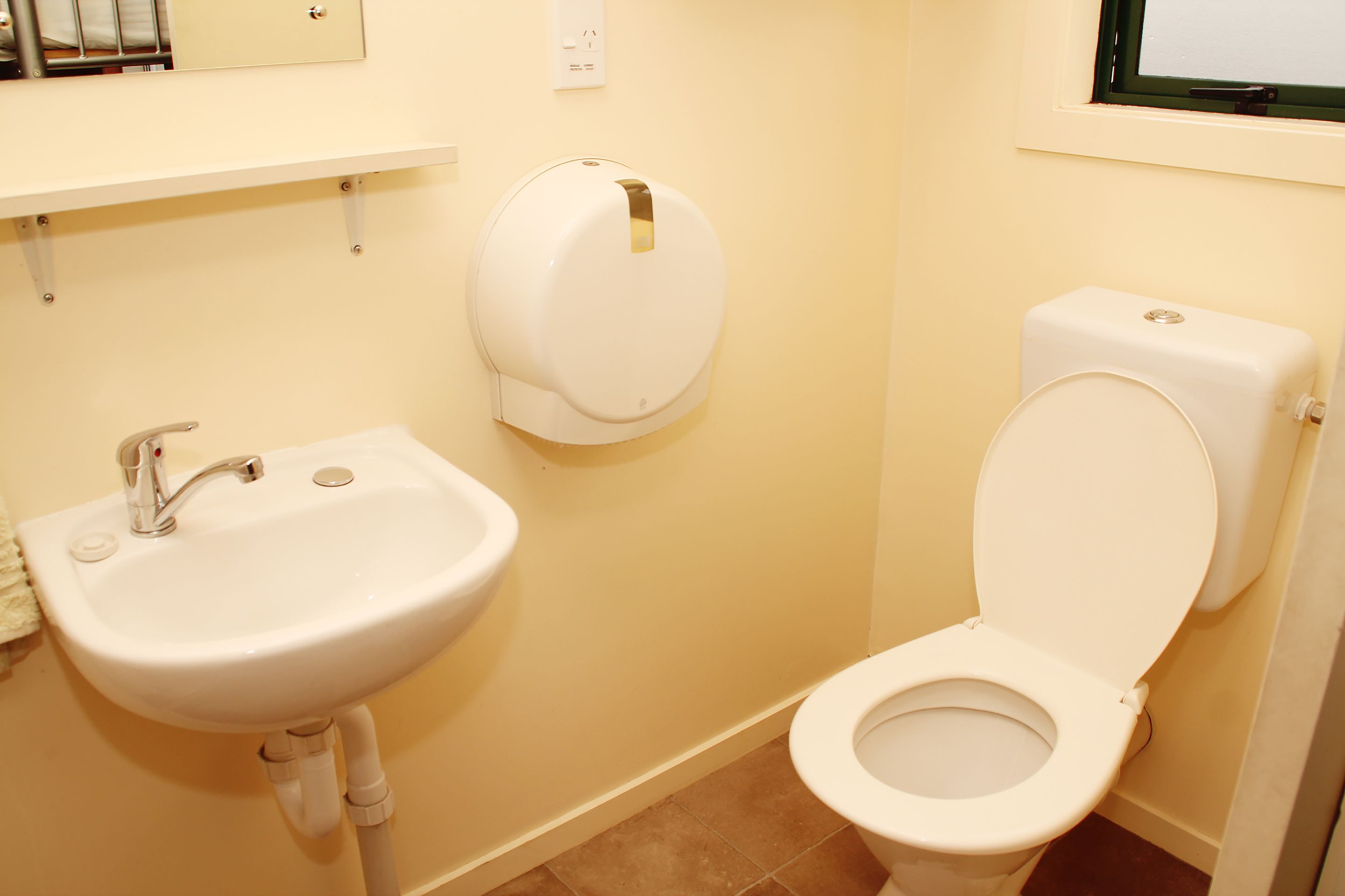 Baño con lavamanos, inodoro y dispensador de toallas de papel.