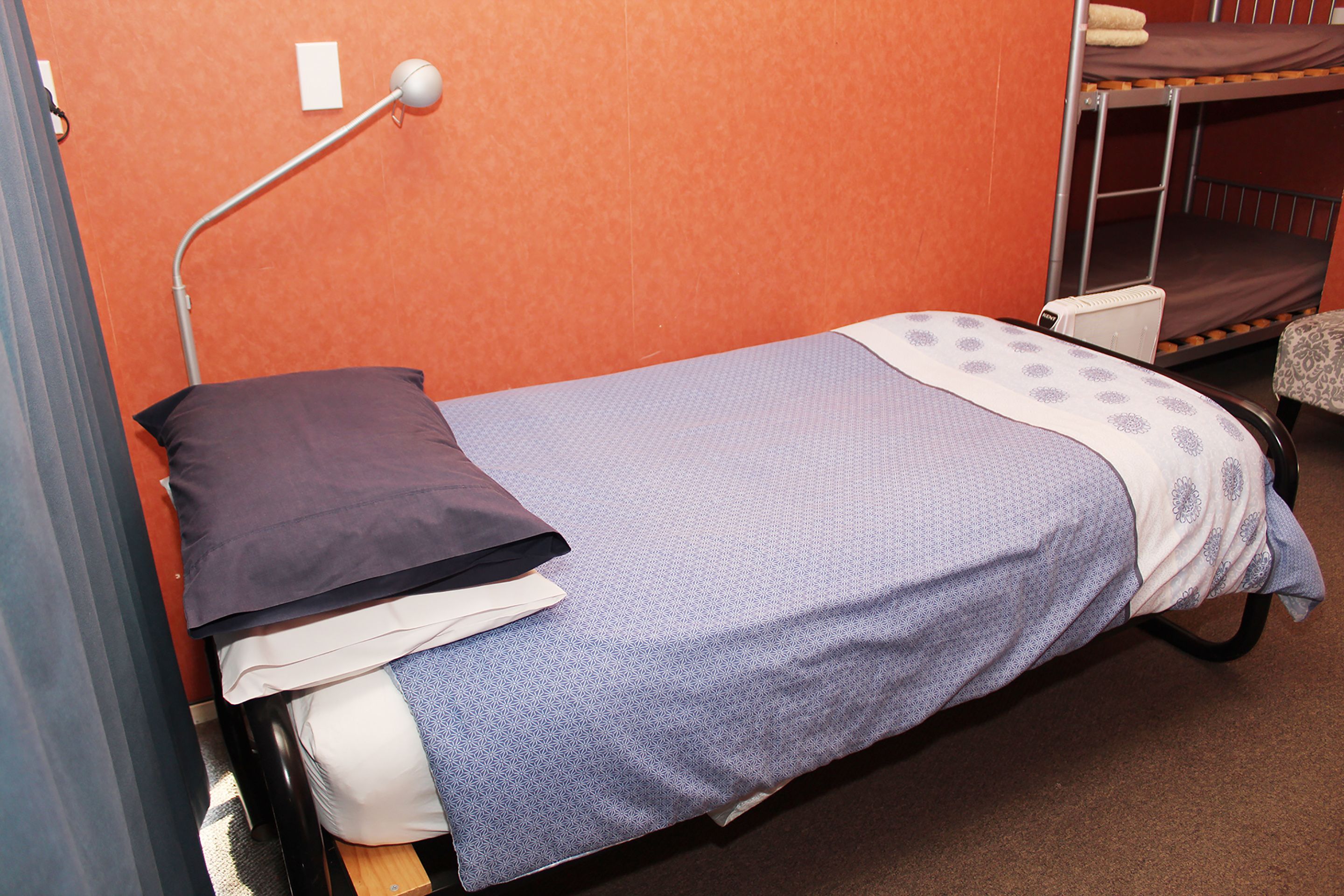 Una cama individual con cabecera, una mesita de noche y una lámpara.
