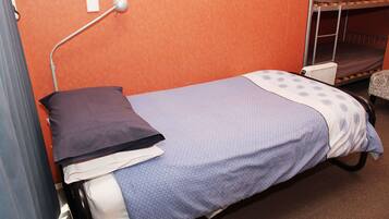 Una cama individual con cabecera, una mesita de noche y una lámpara.