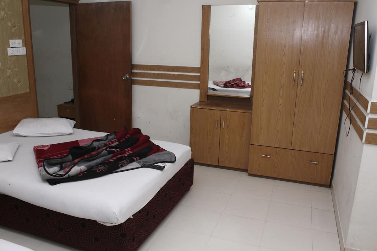 Une chambre à coucher avec un lit, une armoire, un miroir et un téléviseur.