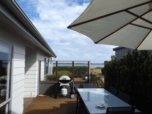 Un patio con mesa y sillas, una parrilla y vistas al agua.