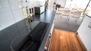 Une cuisine moderne avec un poêle noir, des carreaux blancs et un coin repas comprenant des chaises et une table blanches.