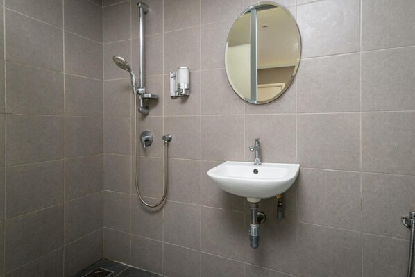 Une salle de bain avec une douche, un lavabo et un miroir.