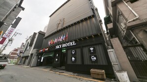 Ein Hotel mit einem Schild, das „SKY HOTEL“ zeigt, und Flaggen verschiedener Länder.