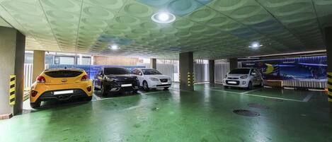 A multi-level parking garage with three cars parked on the ground floor.