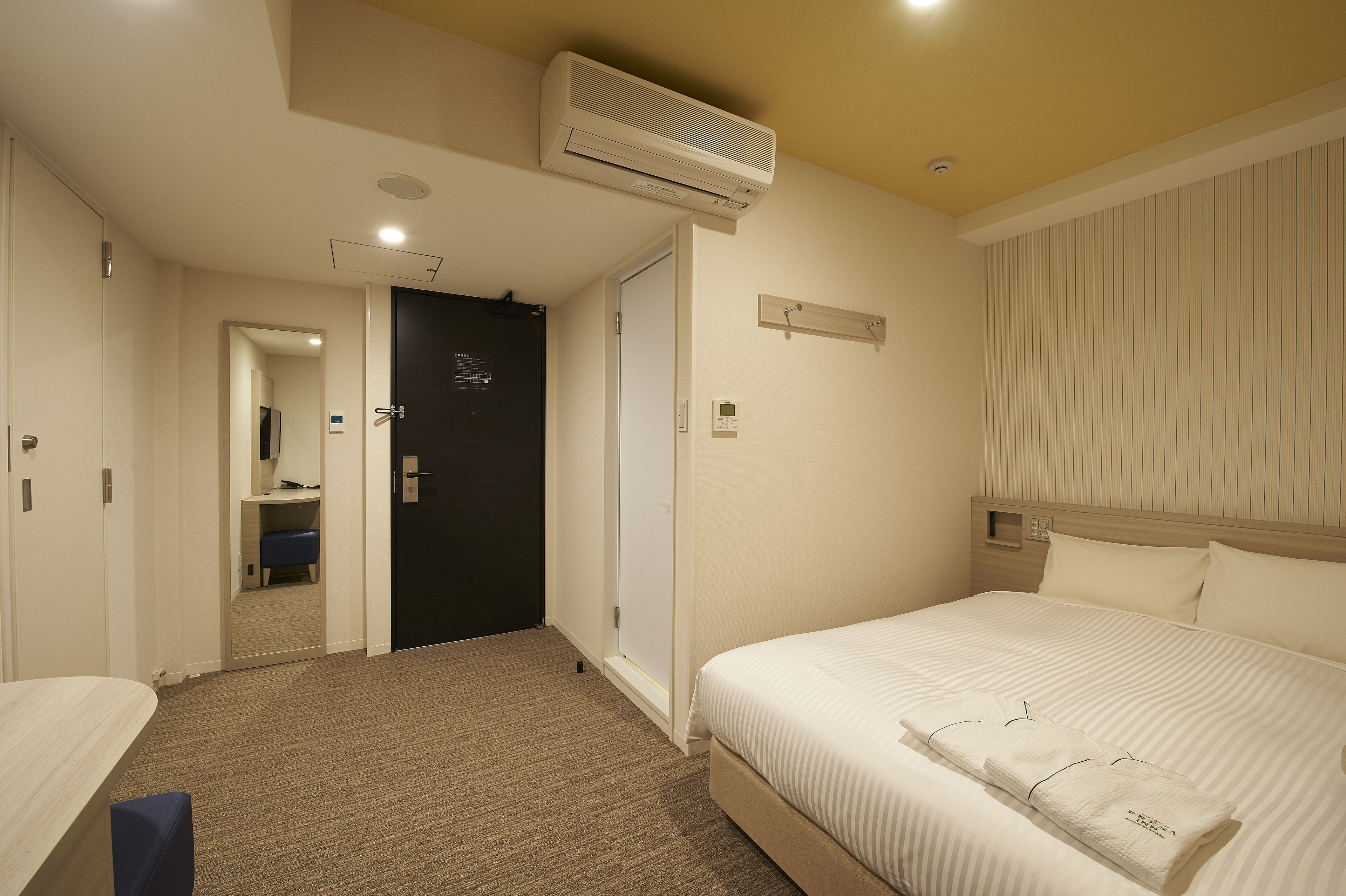 Une chambre d’hôtel avec un lit, un bureau et une armoire.