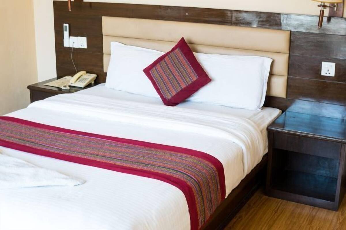 A hotel room with a bed, a bedside telephone, and a nightstand.