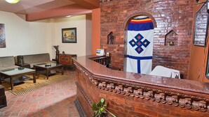 A lobby with a reception desk, seating area, and a decorative wall. - Hotel Namtso (Kathmandu)