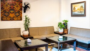 A room with a sofa, two glass-top tables, a potted plant, and artwork on the walls. - Hotel Namtso (Kathmandu)