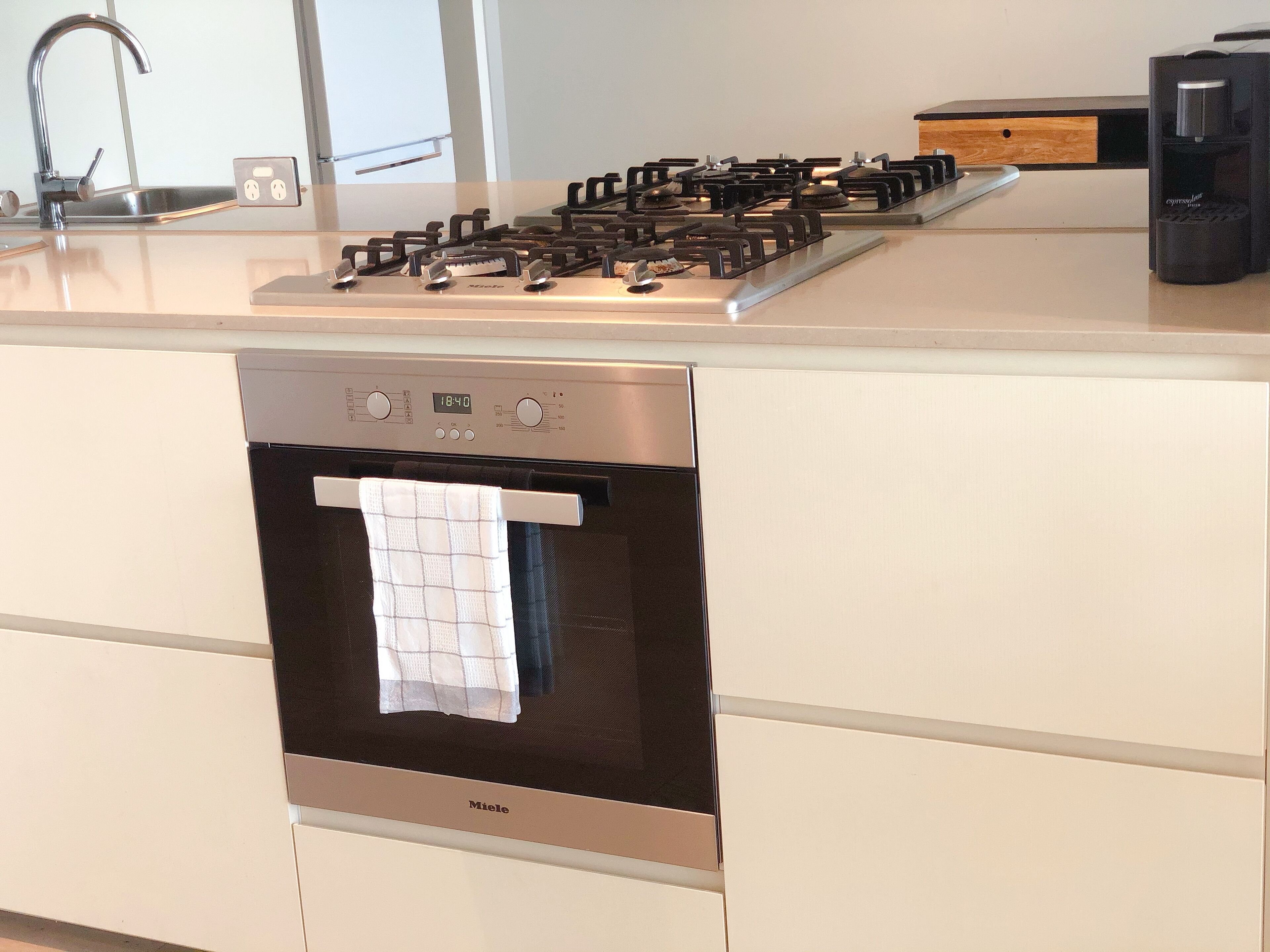 Una cocina moderna con horno empotrado, estufa a gas y cafetera.