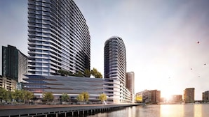 Un immeuble moderne de grande hauteur, doté d’une façade incurvée, situé près du bord de l’eau.