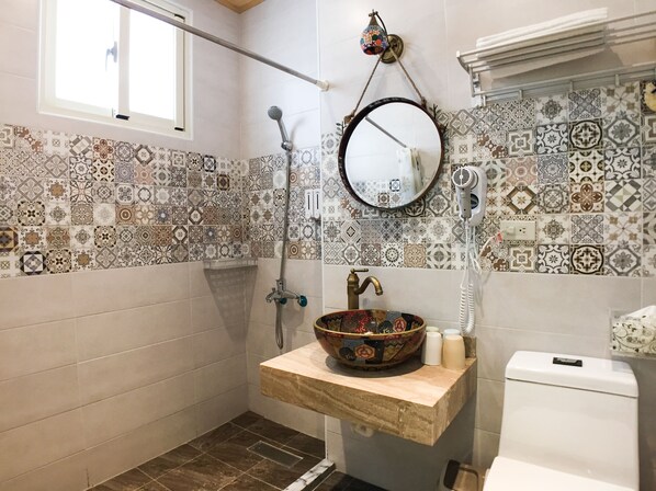 A bathroom with a tiled wall, a hanging mirror, a shower, and a sink with a decorative bowl. - Hualien Bigbowl B&B (Ji'an)