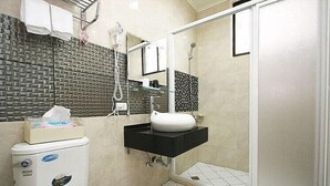 Une salle de bain équipée d’un WC, d’un lavabo, d’une douche et d’un porte-serviettes.