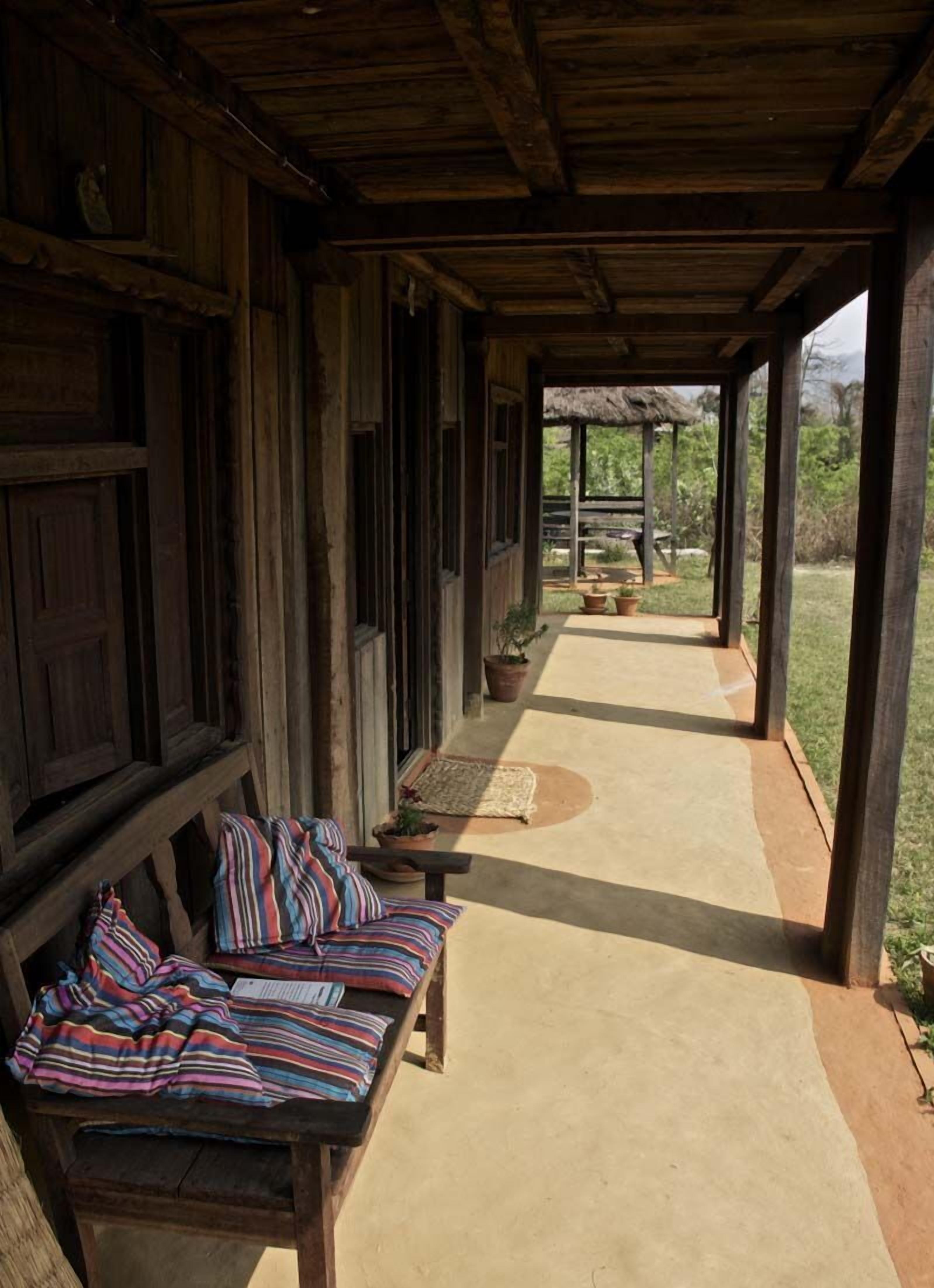 A covered outdoor seating area with benches and a thatched roof structure.