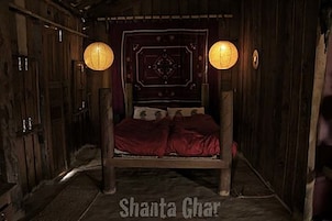 Una habitación de madera con una cama, dos lámparas fijadas a la pared y un cabecero estampado.