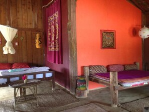 A room with a bed, a small table, a hanging light fixture, and a wall with a framed picture. - Shanta Ghar Resort (Madi)