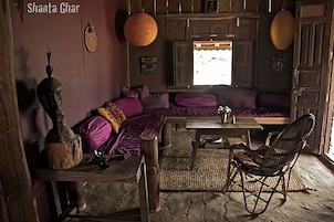 Una habitación tradicional con sofá, una mesa de madera y una silla de mimbre.
