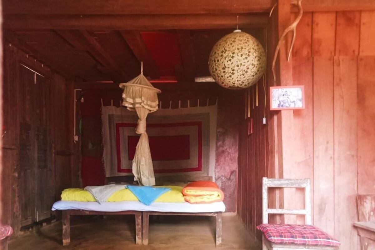 Um quarto de madeira com uma cama, um candeeiro pendente e uma luminária na parede.