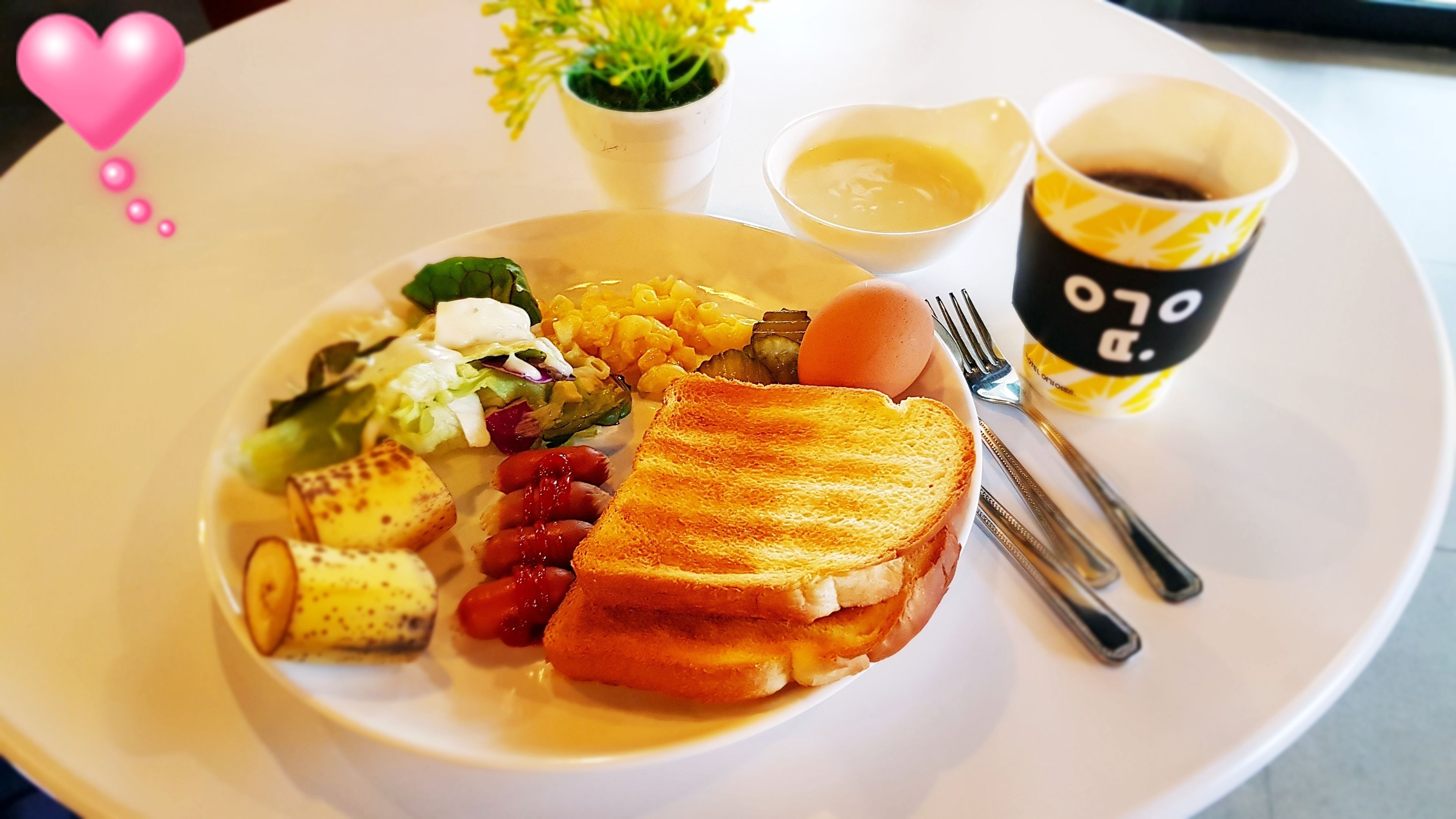 A plate with a sandwich, salad, and macaroni and cheese. There are also two cups, one with coffee and one with a yellow drink.