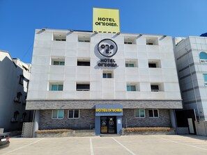 Un moderno edificio de hotel con una fachada perforada distintiva, múltiples ventanas y un llamativo letrero amarillo que indica su nombre.