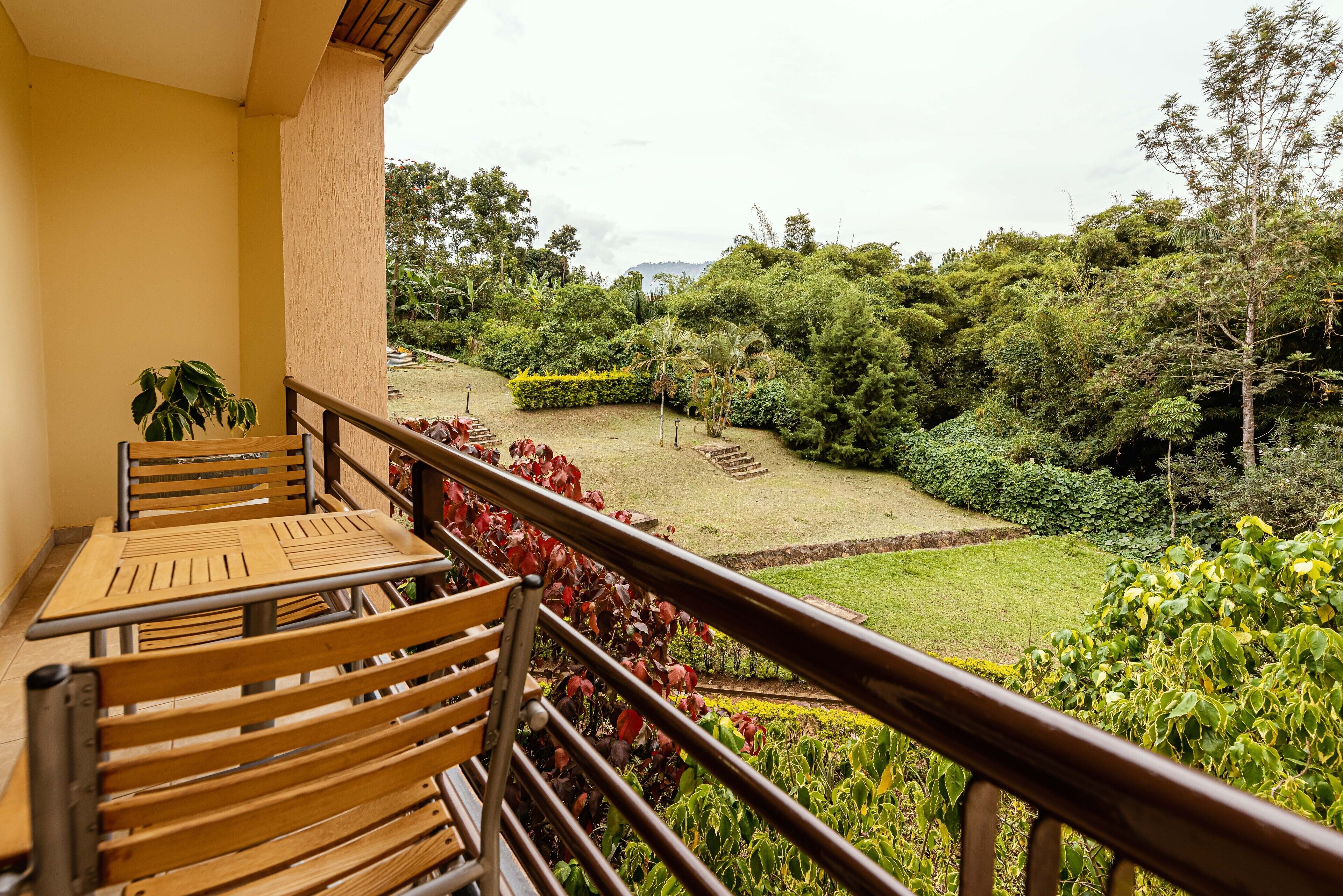 A balcony with wooden furniture and a view of a lush garden.