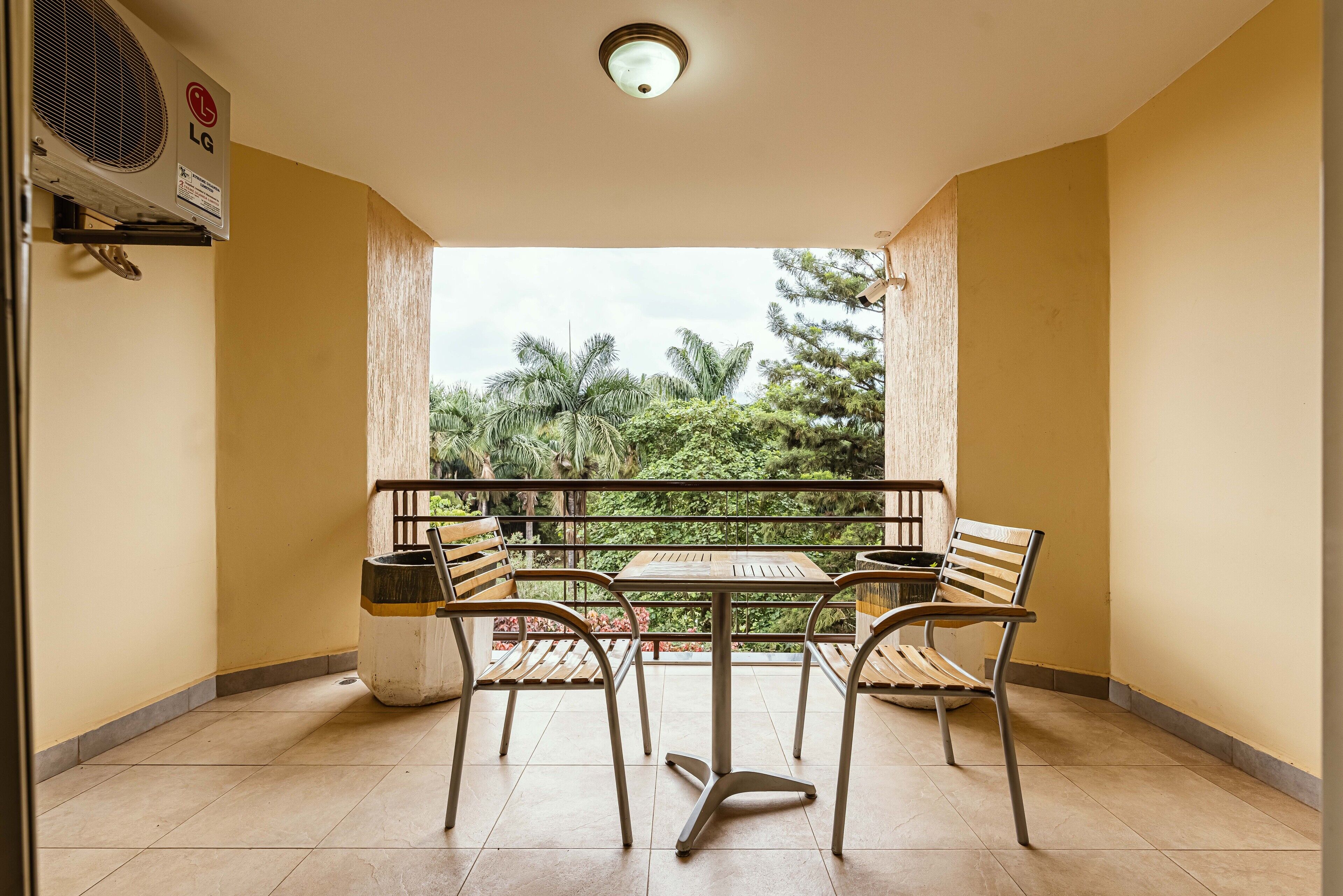 A balcony with a table and chairs, an air conditioning unit, and a view of greenery.