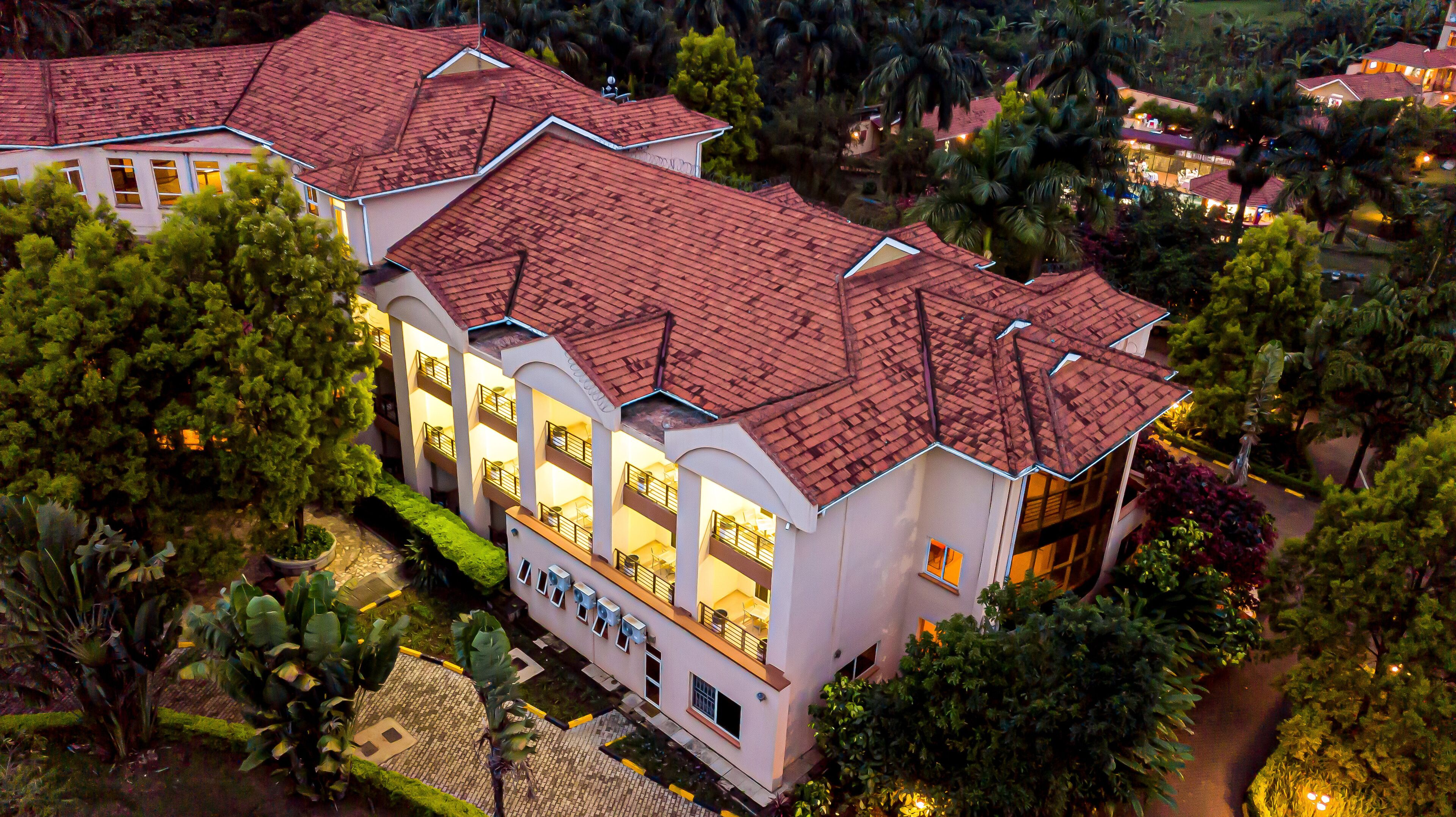 A multi-story building with a red-tiled roof, multiple balconies, and a well-maintained garden area.