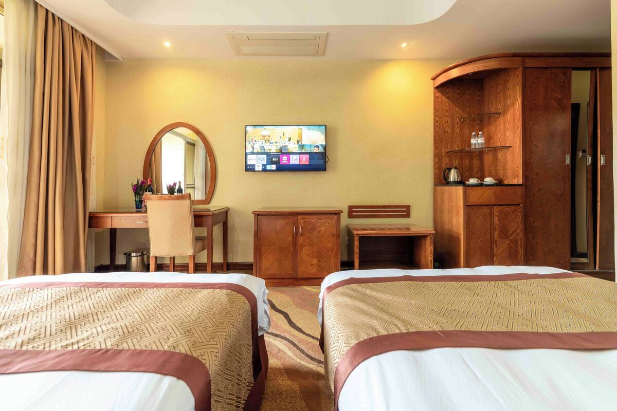 Ett hotellrum med två sängar, ett skrivbord med en stol, en tv och en garderob.