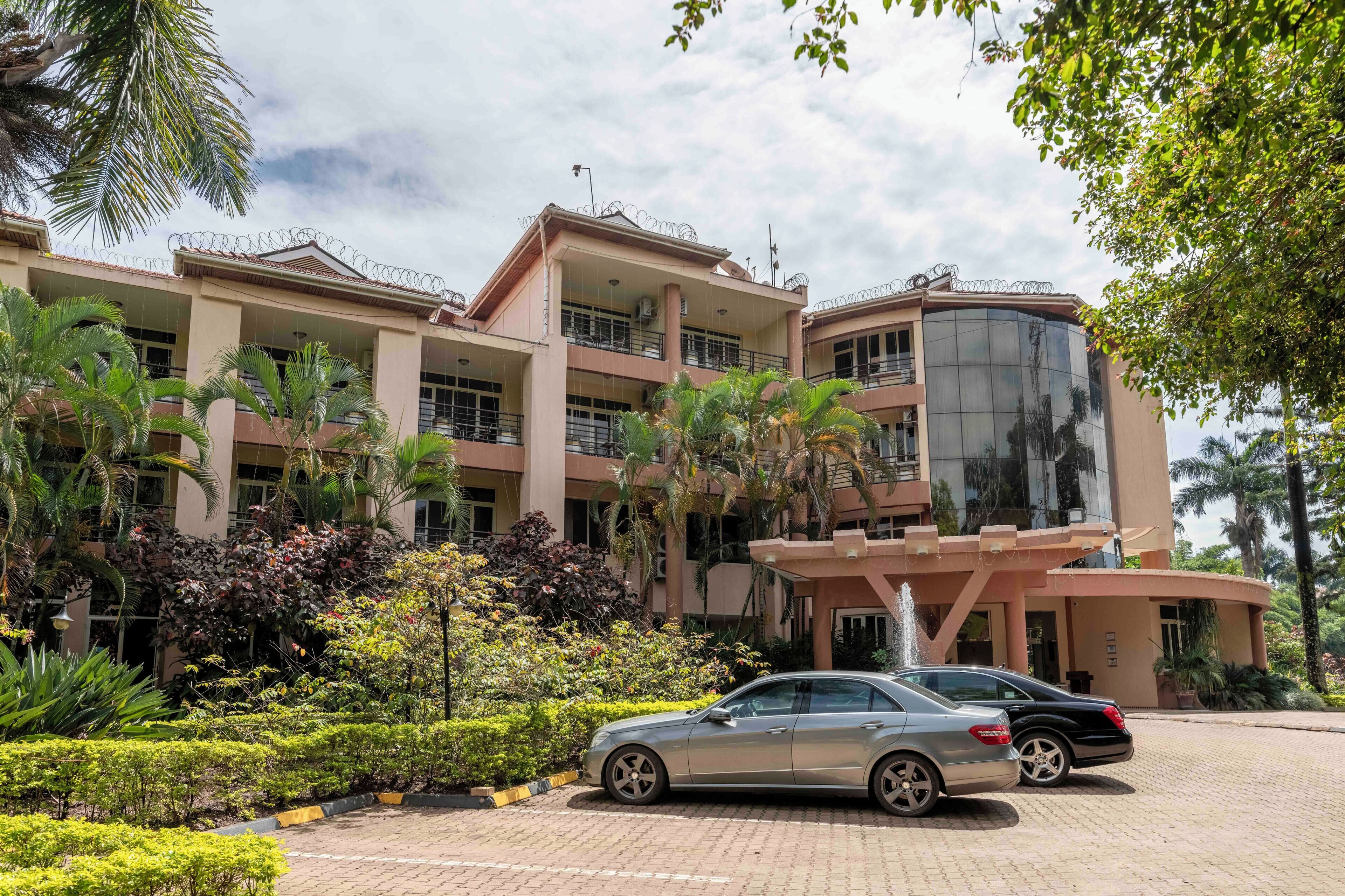 A multi-story building with a central courtyard, surrounded by lush greenery and palm trees.