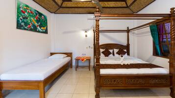 A room with a four-poster bed, a smaller single bed, a painting on the wall, and a ceiling fan.