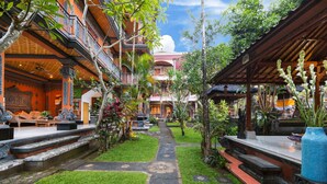 A courtyard with a central pathway, surrounded by lush greenery and traditional architecture. - Sayong House (Ubud)