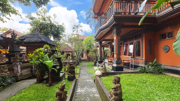 A courtyard with a stone pathway, statues, and traditional architecture. - Sayong House (Ubud)