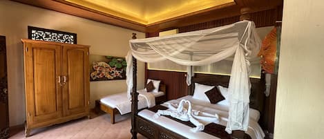 A room with two beds, one with a canopy, a wooden wardrobe, and a decorative wall piece.