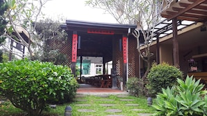A traditional Japanese-style entrance with a wooden gate and red banners, surrounded by lush greenery and stone pathways. - Lins Ju Homestay (Yuchi)