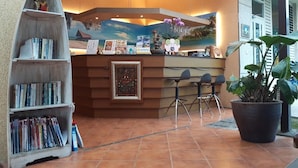A reception area with a wooden counter, a bookshelf, and a potted plant. - Lins Ju Homestay (Yuchi)